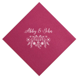 The Garden Flourish Napkin design exudes old-world romance. The couple's names are elegantly scripted in a swirling, romantic font. Below, a whimsical cascade of florals and greenery, dotted with hidden hearts and interspersed flowers, evokes the charm of a bride's cascading bouquet.