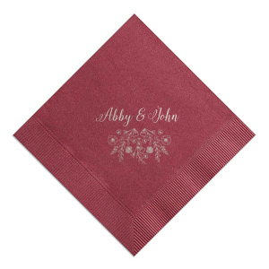 The Garden Flourish Napkin design exudes old-world romance. The couple's names are elegantly scripted in a swirling, romantic font. Below, a whimsical cascade of florals and greenery, dotted with hidden hearts and interspersed flowers, evokes the charm of a bride's cascading bouquet.