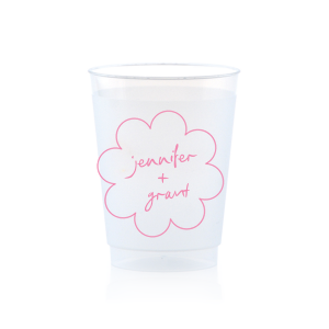 Sip in style at your whimsical wedding with the Kitschy Cocktail Hour Floral Frame Cup. Personalize this charming vessel with the couple's names, elegantly scripted within a blooming flower-shaped frame. A modern and enchanting choice for your celebratory toasts.