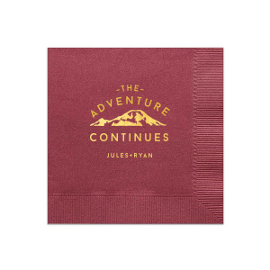 The Adventure Continues Napkin design encapsulates the spirit of exploration and shared journey. Featuring a graphic of snow-capped mountains with "The Adventure" arching over and "CONTINUES" below, it symbolizes the ongoing journey of the couple. Their names personalize this narrative of continuous adventure and discovery as they embark on life together. 