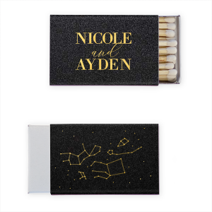 The Written in the Stars Matchbox dazzles with celestial charm. One side features "written in the stars" in twinkling script amidst a constellation graphic, capturing a heavenly feel. The other side proudly displays the event stars' names in bold all-caps, anchoring the cosmic theme.