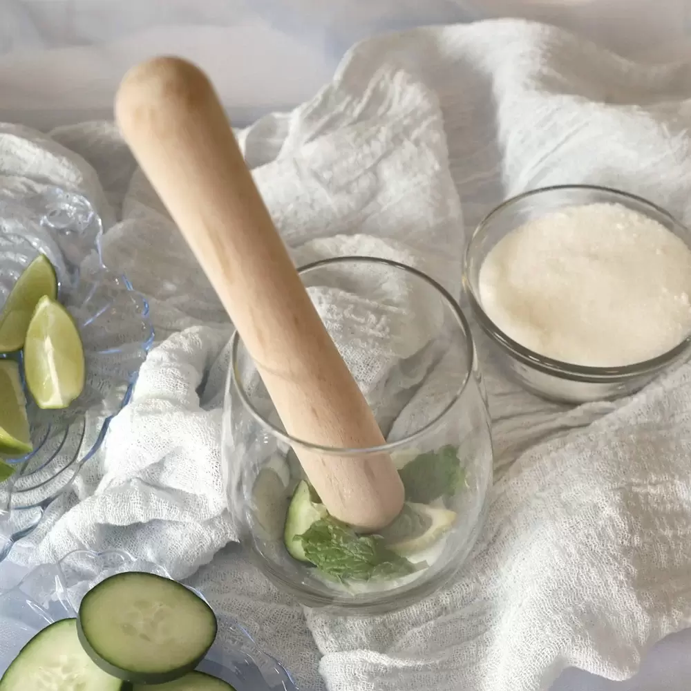 Rolling pin being used to muddle lime, mint, and sugar