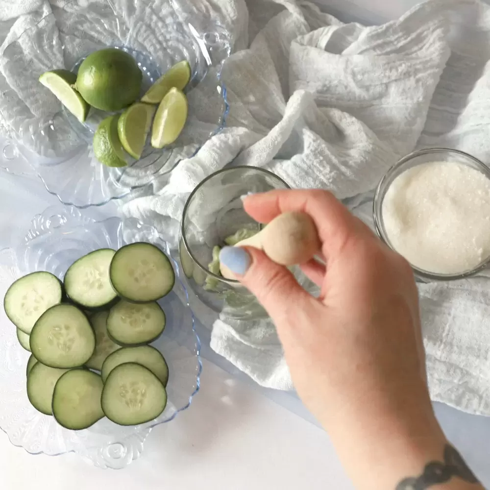Muddling cucumber mojito ingredients with hand in the picture 