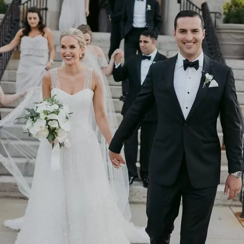 couple wearing black tie holding hands in front of a staircase, front image of wedding dress code guide. 