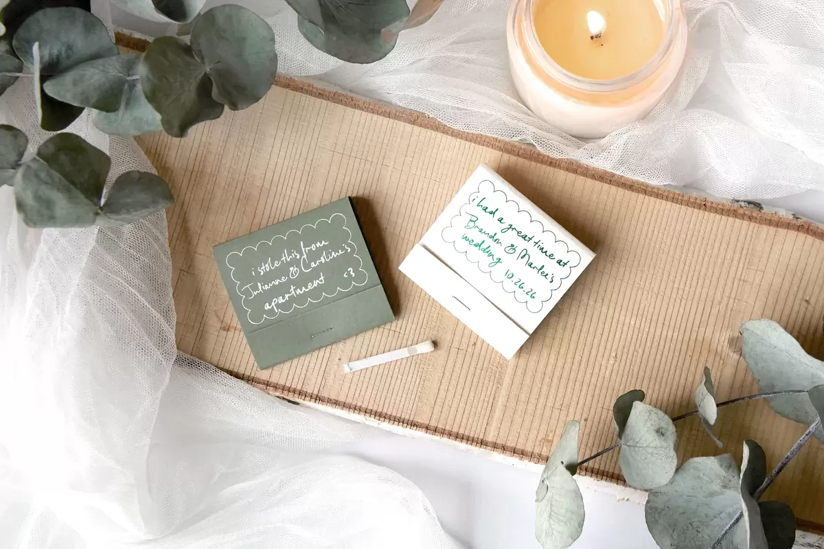 Two matchbooks laying flat on a table next to a candle